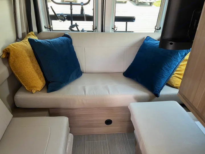 Cozy RV rental interior with a light sofa, colorful pillows, and TV, perfect for travel comfort.. Thor Sequnce 2023
