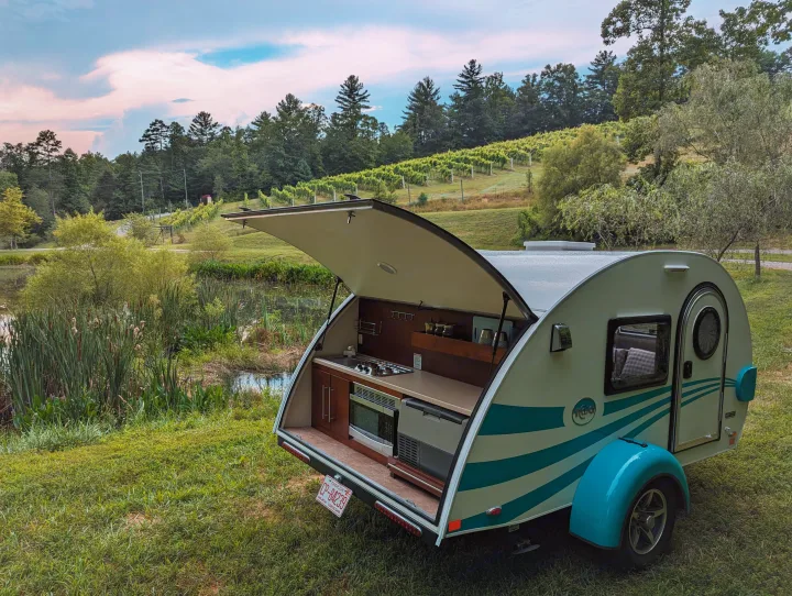 This cozy teardrop RV rental, with its outdoor kitchen, is perfectly set by a pond and vineyard for a serene camping trip.. nuCamp T@G 2017