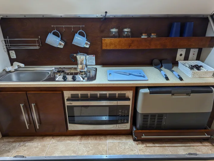 This RV rental offers a well-equipped kitchen with a sink, stove, microwave, and portable fridge.. nuCamp T@G 2017