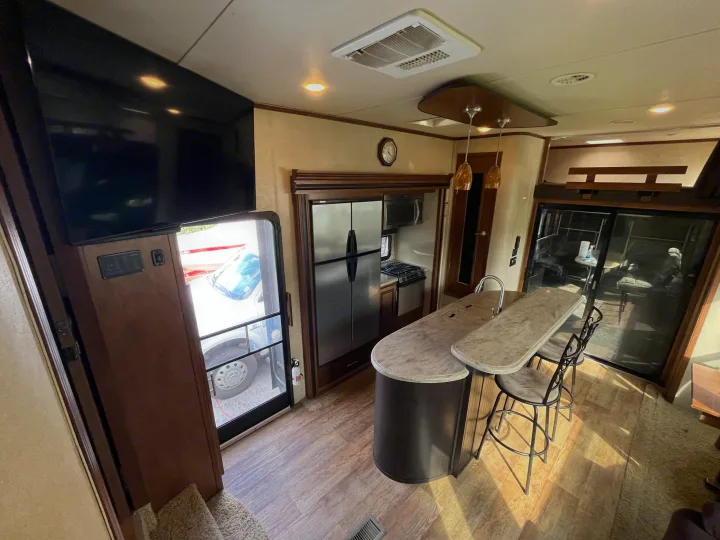 Spacious RV rental interior featuring a modern kitchen with island seating, refrigerator, and bright living space.. Forest River XLR Thunderbolt Toy Hauler 2015