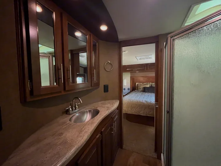 RV rental with a functional bathroom featuring a sink, vanity, and shower, adjacent to a comfortable bedroom.. Forest River XLR Thunderbolt Toy Hauler 2015