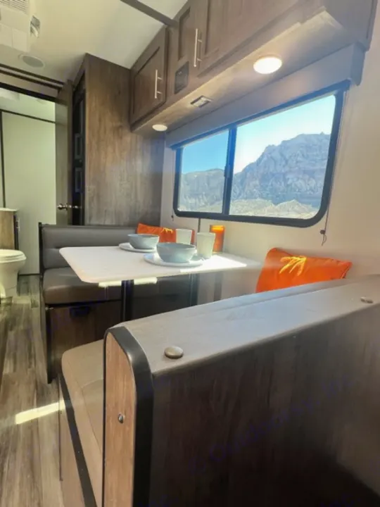 RV rental interior: A bright space with wooden cabinets, a comfortable dinette, and a large window framing a mountain view.. Riverside Retro 190BH 2023