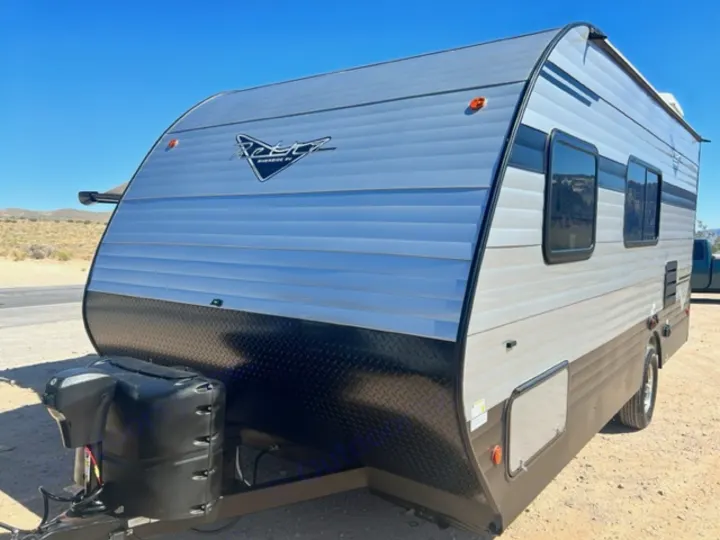Ready for adventure! This modern silver/black travel trailer, ideal for rv rental, is parked in a sunny, desert setting.. Riverside Retro 190BH 2023