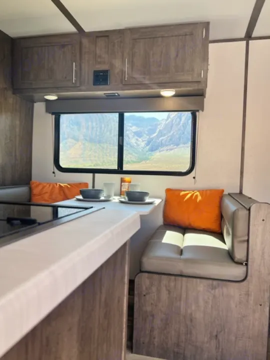 Inside an RV rental: Cozy dinette with mountain views & storage. Ideal for road trips!. Riverside Retro 190BH 2023