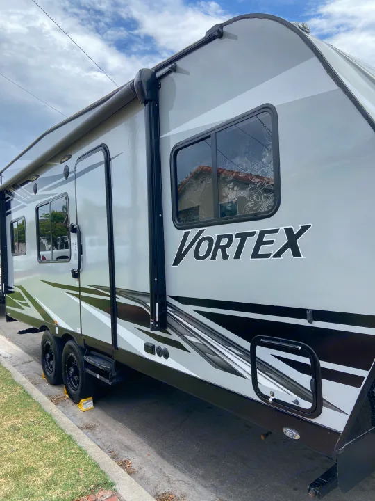 RV rental: Modern grey Vortex travel trailer parked street-side, ready for your next outdoor journey.. Genesis Supreme Rv Genesis Supreme 2022