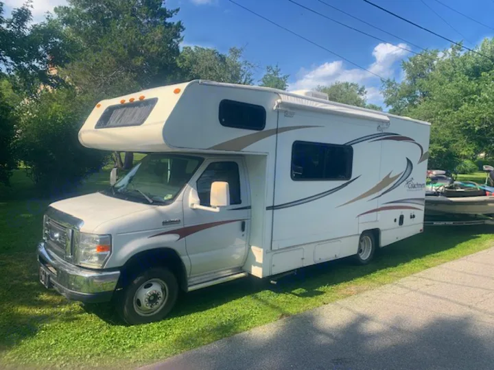 White Coachmen Class C RV rental towing a boat, ready for outdoor adventures on a sunny day.. Other Other 2014
