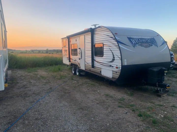 **RV rental** travel trailer parked in a field at sunset, ready for your next outdoor adventure.. Forest River Wildwood X-Lite 2017