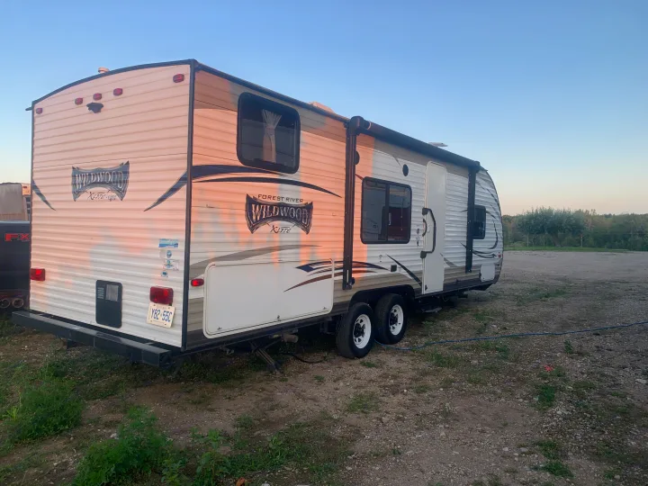 Light-colored Forest River Wildwood X-Lite travel trailer RV rental, parked on gravel, ready for adventure.. Forest River Wildwood X-Lite 2017