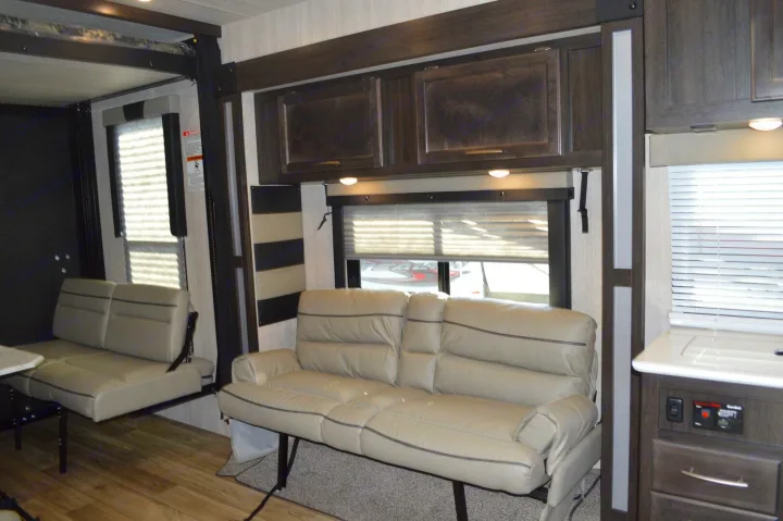 RV rental interior features a spacious, convertible sofa, overhead cabinets, and adaptable seating, perfect for travel comfort.. Genesis Supreme Rv Genesis Supreme 2024