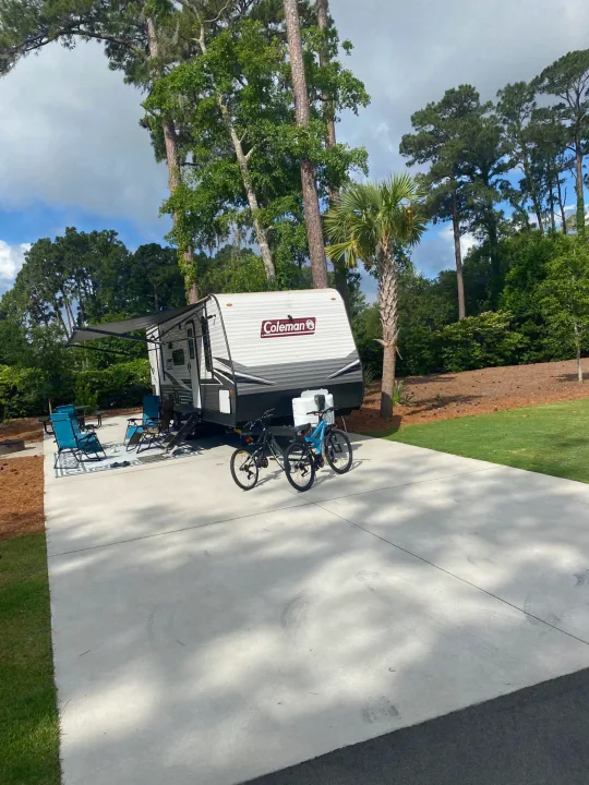 RV rental at a scenic campsite, featuring an awning, outdoor chairs, and bikes on a concrete pad, ready for adventure.. Coleman Lantern 2021