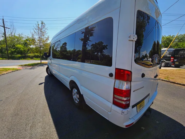 White Mercedes Sprinter van, perfect for RV rental or group trips. Parked on a sunny day, trees reflected in tinted windows.. Mercedes-Benz Sprinter 2017