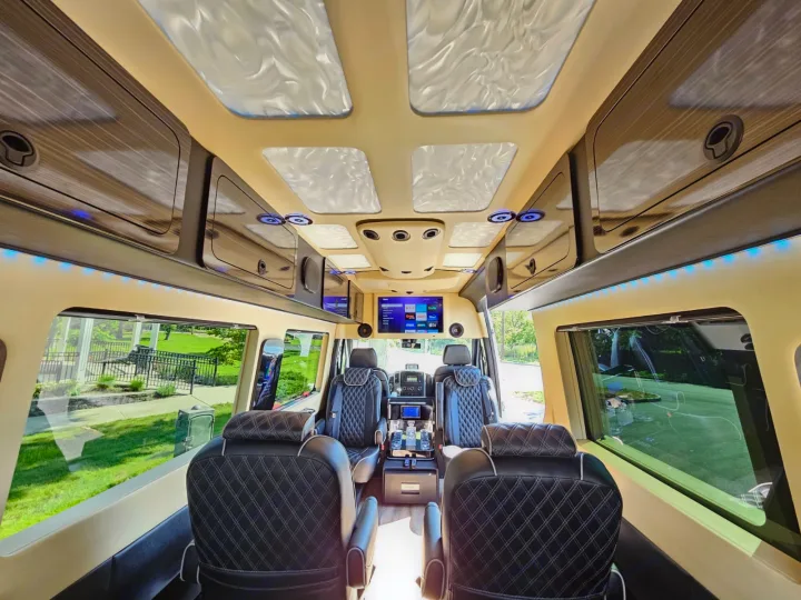 Luxury RV rental: interior with black quilted leather seating, entertainment screens, ambient blue lights, and overhead storage.. Mercedes-Benz Sprinter 2017