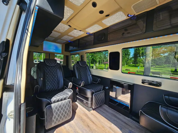 The inviting interior of a luxury rv rental van with black quilted seats, a TV, and accent lights seen through large windows.. Mercedes-Benz Sprinter 2017
