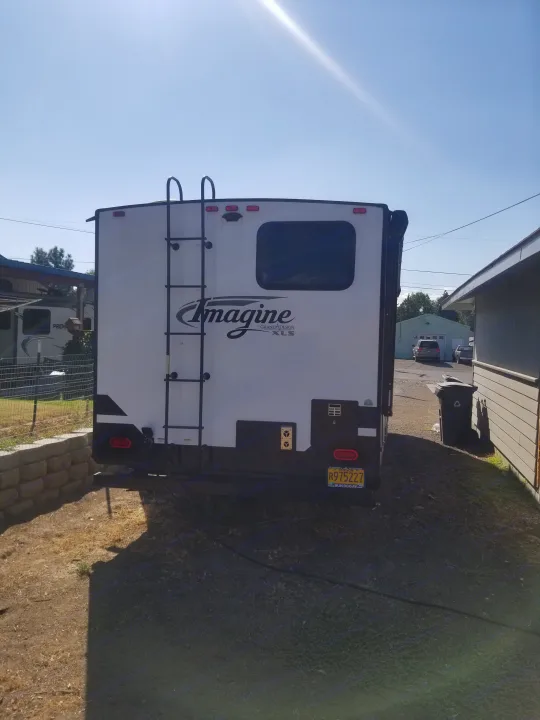 Back of a white Grand Design Imagine travel trailer parked outdoors, ready for RV rental.. Grand Design Imagine XLS 2021