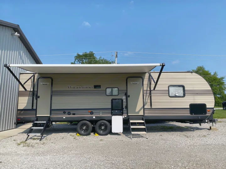 RV rental: A beige Wildwood travel trailer with an extended awning, parked on gravel.. Forest River Wildwood 2020