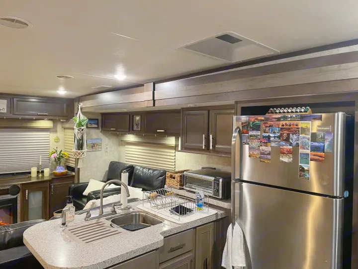RV rental interior: compact kitchen with sink, fridge, toaster oven; adjacent living area features sofa and fireplace.. Highland Open Range 2017