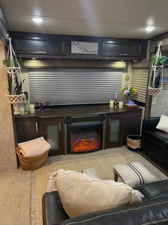 Cozy RV rental living space featuring a glowing fireplace, soft lighting, and inviting home decor details.. Highland Open Range 2017