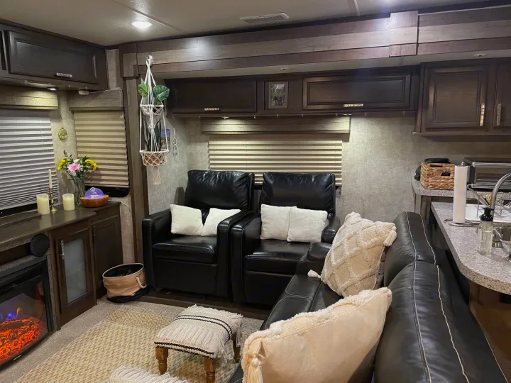 Cozy RV rental living space with dark leather seating, a fireplace, and warm decor. Perfect home on wheels.. Highland Open Range 2017