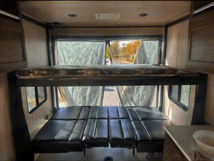 RV rental interior: A top bunk bed & lower convertible sofa, with screened windows, offers versatile sleeping options.. Genesis Supreme Rv Powerlite Prime 1915 2022