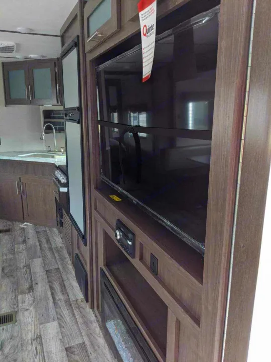 Modern RV rental interior featuring a full kitchen and a cozy entertainment center with TV/fireplace.. Keystone RV Hideout Luxury 2021