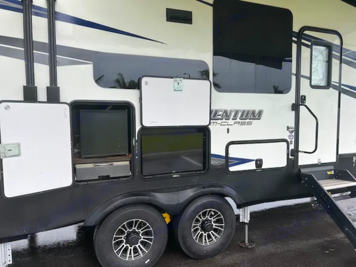 RV rental's side: open outdoor kitchen with fridge, TV, and storage bays. Ideal for travel and camping adventures.. Grand Design Momentum 2018