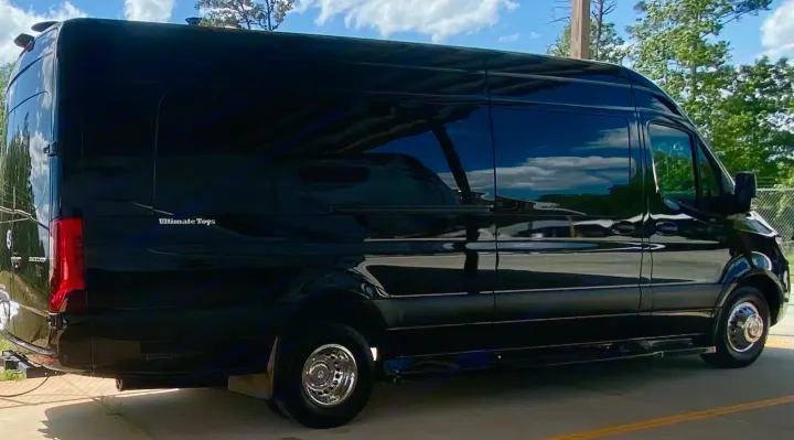 Sleek black "Ultimate Toys" luxury van, a high-end RV rental. Features tinted windows, chrome wheels & a polished finish.. Ultimate Toys Ultimate Coach 2024