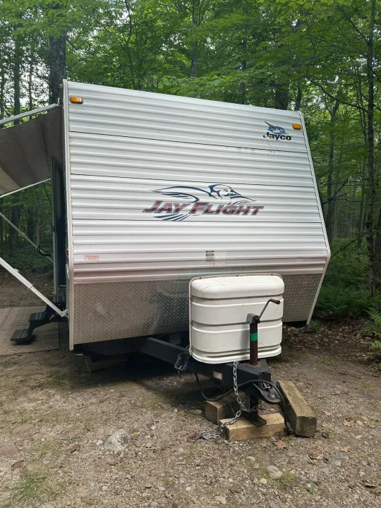 This RV rental, a white Jayco travel trailer, is parked at a shaded campsite, ready for your outdoor adventure.. Jayco Jay Flight 2009