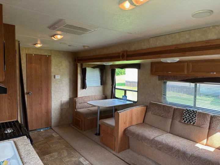 Bright RV rental interior with a cozy dining booth, sofa, and kitchen. Perfect for travel adventures!. Jayco Jay Flight 2009