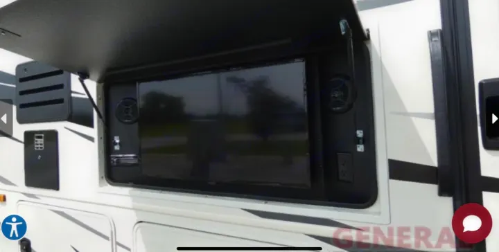 Side of an RV rental with its exterior entertainment bay open, revealing a large TV, speakers, and power outlets for outdoor viewing.. Entegra Coach Vision 2023