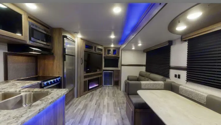 Modern rv rental interior: full kitchen, living area with TV & fireplace, and dining booth. Well-appointed for travel.. Crossroads RV Zinger 2020