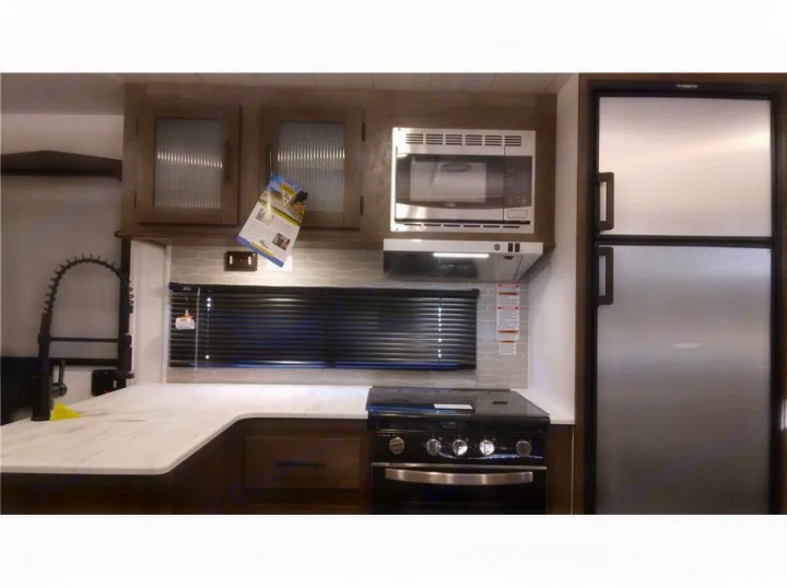 Well-equipped rv rental kitchen: sleek counter, sink, microwave, gas oven/stove, and refrigerator. Modern design.. Forest River Salem 2022