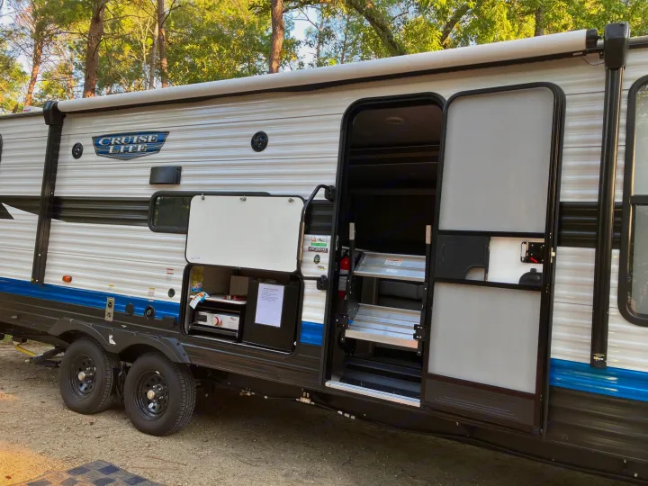 This RV rental is a CRUISE LITE travel trailer, showcasing its open door, steps, and outdoor kitchen.. Forest River Salem Cruise Lite 2023