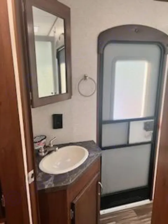 This RV rental bathroom features a compact sink, mirror, and functional door. Essential amenities for travel comfort.. Jayco Jay Flight 2017