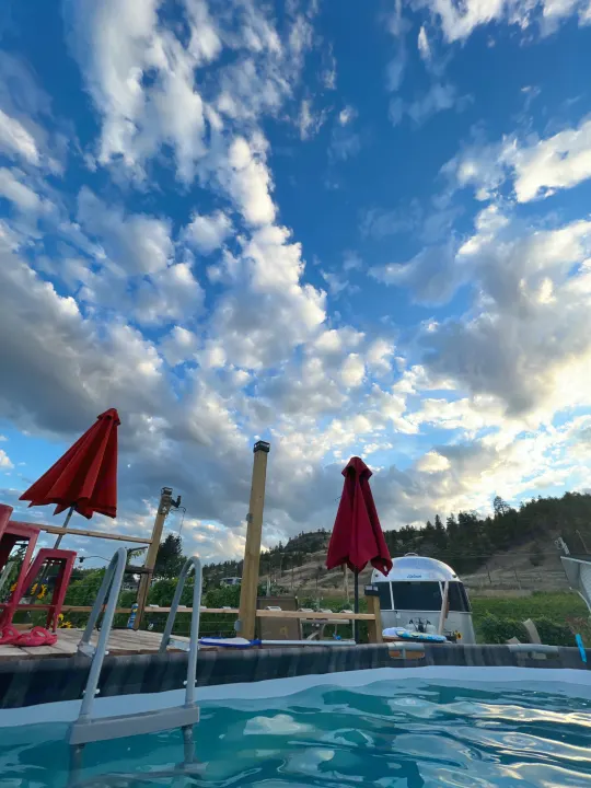 Relax by the pool with an Airstream rv rental, enjoying scenic hillside views under a cloudy sky.. Airstream Sport 2012