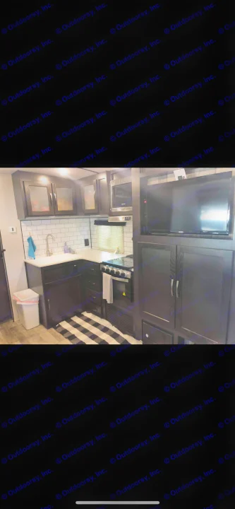 Modern RV rental kitchen featuring dark cabinets, white counters, subway tile backsplash, and essential appliances.. Forest River Legend 2019