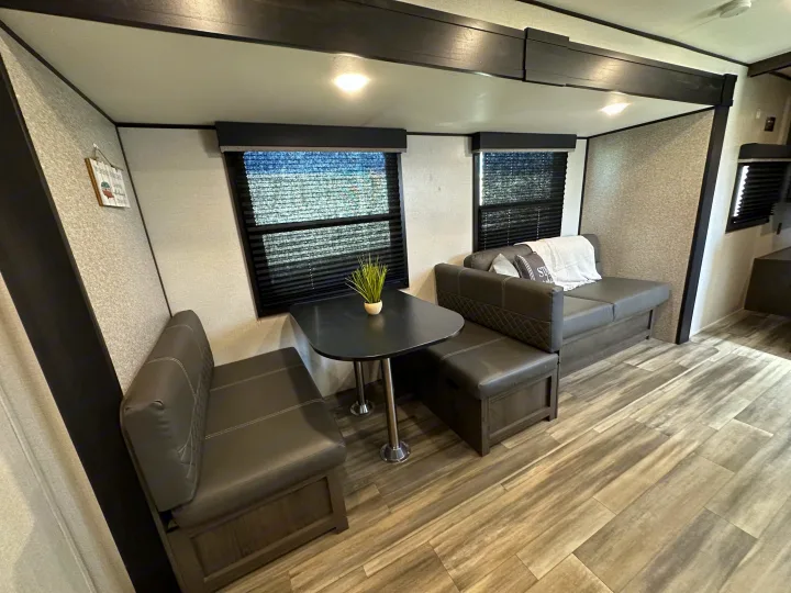 Cozy RV rental living area featuring a booth dinette, sofa, and modern wood-look flooring.. Starcraft Autumn Ridge 2022