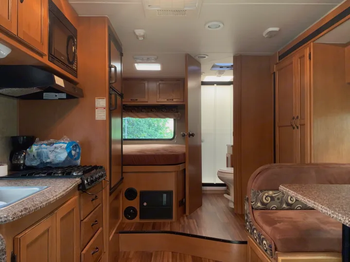 Inside an RV rental: kitchen, bedroom, dinette, and bathroom visible. Compact, functional living space for travel.. Other Other 2014