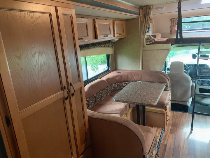 View inside an RV rental showing a comfortable dinette, wood cabinets, and the driver's area.. Other Other 2014