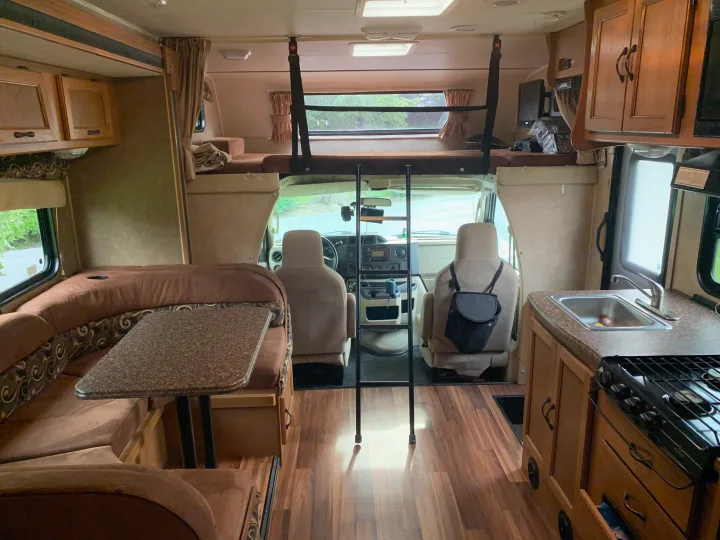 Spacious RV rental interior with an overhead bed, dinette, kitchen, and driver's area for comfortable travels.. Other Other 2014