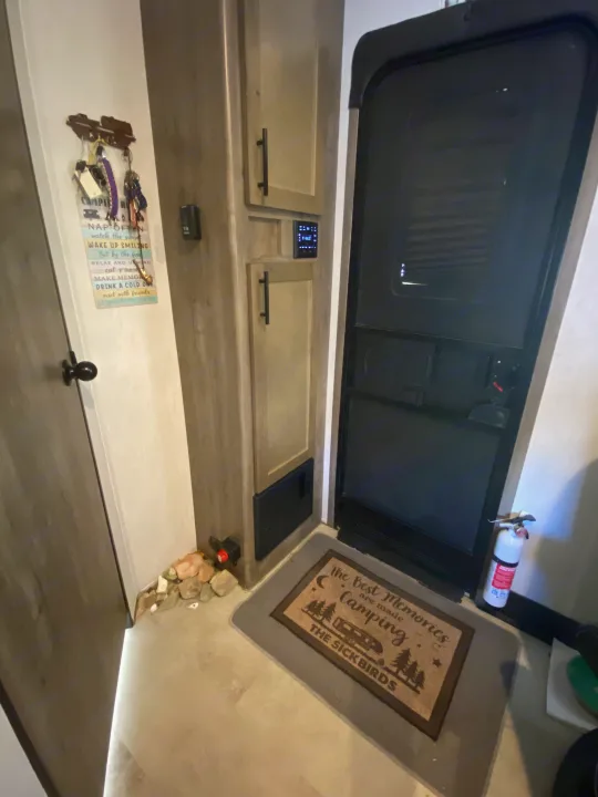 Experience this RV rental: Entrance door, digital control panel, overhead cabinets, fire extinguisher, and a "Camping" welcome mat.. Forest River Vengeance 2021