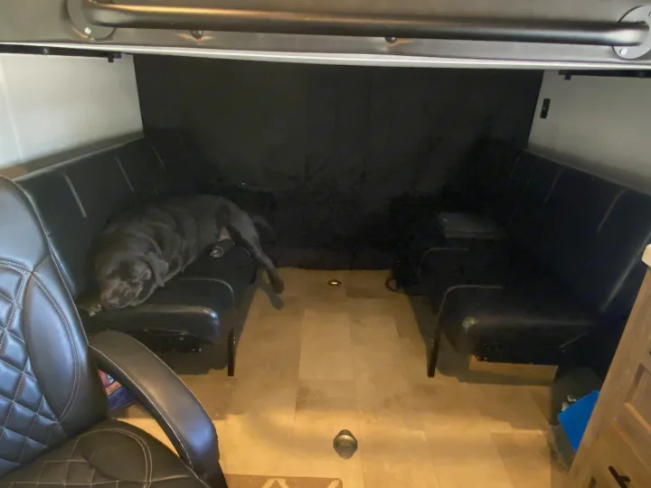 A large, dark dog naps peacefully on a black leather sofa inside an rv rental, showcasing a pet-friendly interior space.. Forest River Vengeance 2021