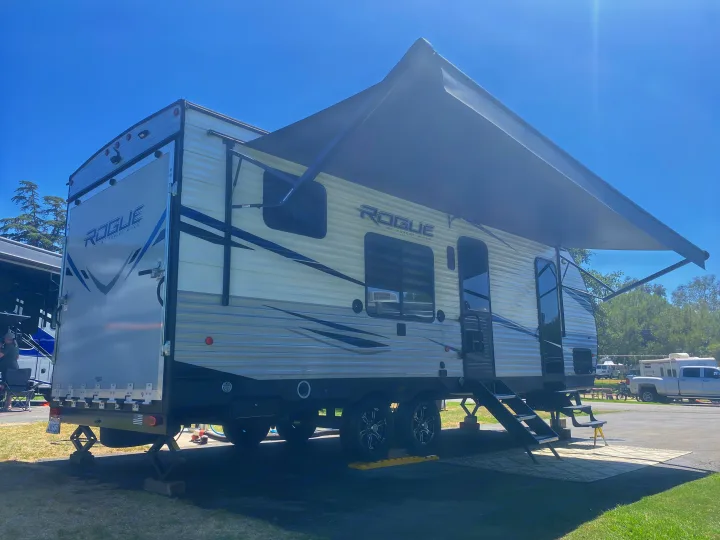 Rogue travel trailer RV rental with extended awning, parked for camping under a sunny sky.. Forest River Vengeance 2021