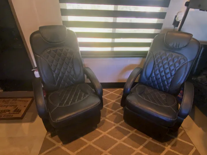 Comfortable black leather recliners with quilted stitching, perfect for relaxing in your rv rental. Enjoy plush seating!. Forest River Vengeance 2021