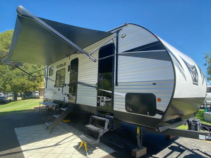 This bright Rogue travel trailer RV rental, parked with an extended awning and dual steps, is ready for your camping adventures.. Forest River Vengeance 2021