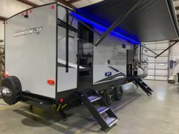 Grey Alpha Wolf travel trailer with blue LED-lit awning. Ideal RV rental for camping and adventure trips.. Forest River Cherokee Alpha Wolf 2022