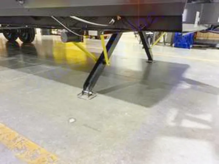 Close-up of an RV rental's extended stabilizer jacks on a concrete floor, providing essential support and leveling.. Forest River Cherokee Alpha Wolf 2022