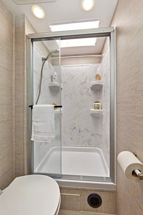 This RV rental bathroom offers a compact, modern design with a glass shower, toilet, and skylight. Clean and efficient space.. Entegra Coach Odyssey 2021