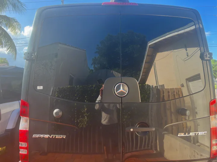 Back of a dark Mercedes-Benz Sprinter van, popular as an RV rental, with reflections on its tinted windows.. Mercedes Sprinter 2016
