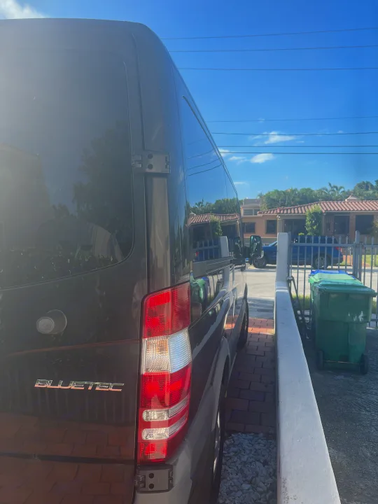 Dark grey Mercedes-Benz Sprinter van, an RV rental, parked on a brick path in a sunny residential area.. Mercedes Sprinter 2016