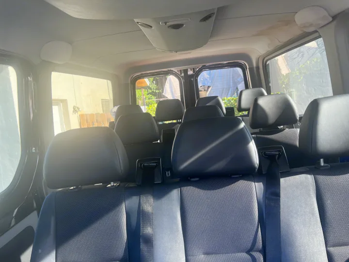 Spacious RV rental interior with multiple rows of black passenger seats, offering ample seating for your group adventures.. Mercedes Sprinter 2016